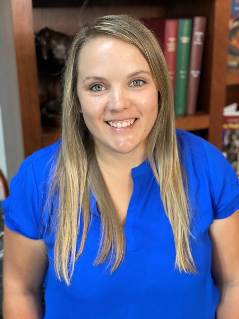 A woman in blue shirt smiling for the camera.