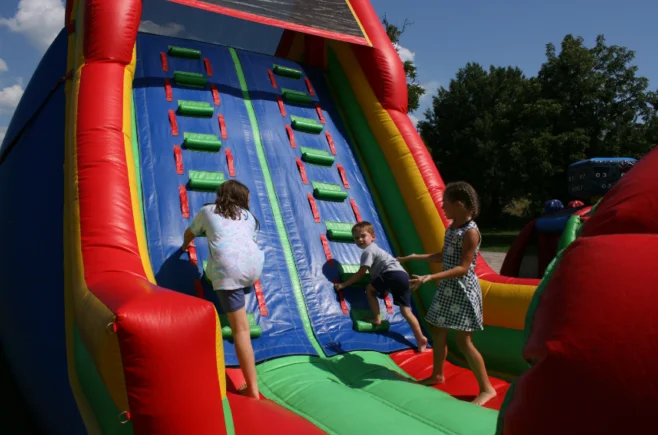 A group of kids playing on an inflatable slide.