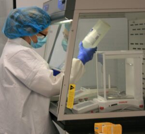 A person in a lab coat and mask working.